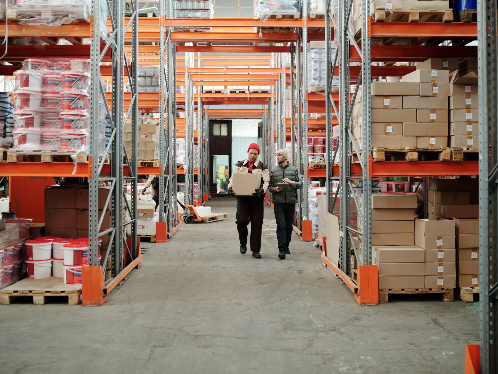 Personal de bodega revisando mercadería entre estanterías de carga